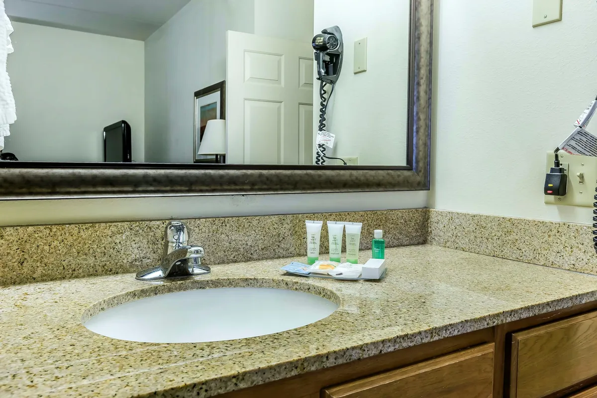 A modern bathroom with a well-lit vanity, a spacious sink, a large mirror, and neatly organized toiletries, including fresh towels on the counter. The clean lines and inviting setup reflect the attention to guest comfort and care.