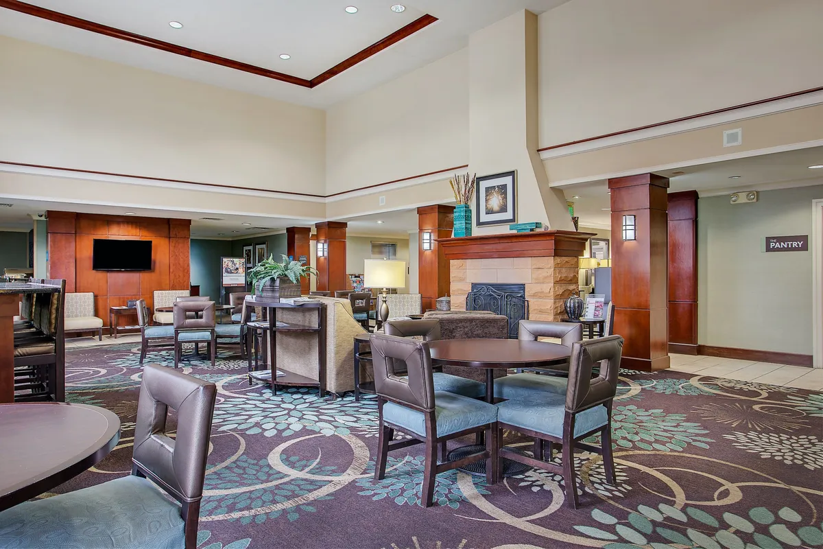 A cozy interior featuring a fireplace, comfortable seating, and decorative plants. The area is ideal for relaxation, reading, or spending time with companions, and it radiates a sense of comfort and homeliness.