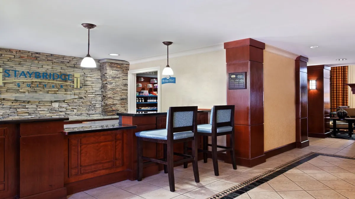 This image captures the welcoming reception desk with a stone wall backdrop, comfortable seating area, and warm light fixtures. The space feels inviting and organized, suggesting attentive service and a smooth check-in experience for guests.